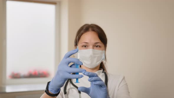 Closeup of a Female Doctor in a Medical Mask Holding an Insulin Syringe She