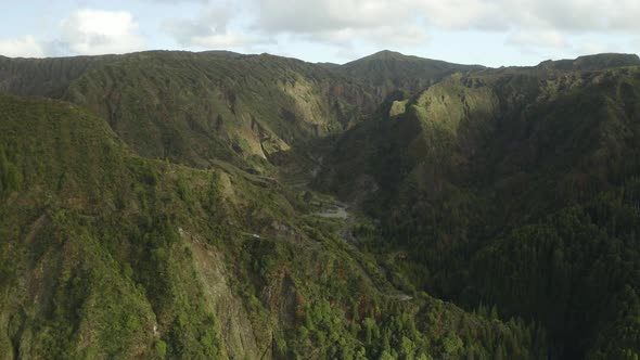Two cars make their way through the winding roads of the Azores, aerial establishing shot