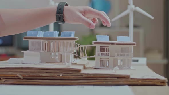 Close Up Of Man's Hand Putting The Solar Panel On The Roof Of A Small Model House