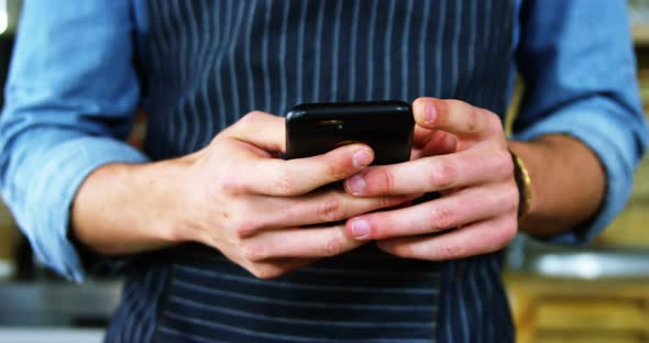 Male waiter using mobile phone