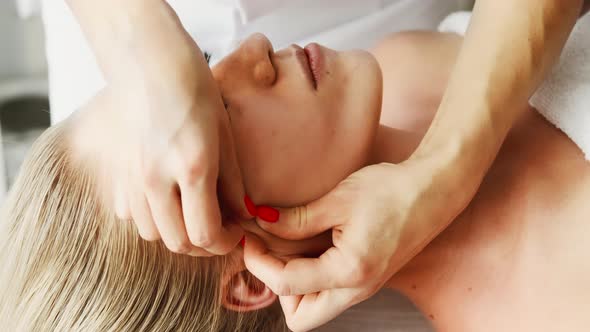 Beautician cosmetologist makes lifting face massage, pinch and roll technique