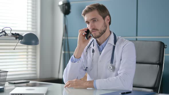 Doctor Talking on Smartphone While Sitting in Clinic