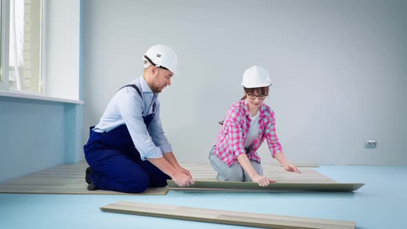 Male and Female Construction Team in Slots Lay Laminate Flooring During Home Renovation and Home