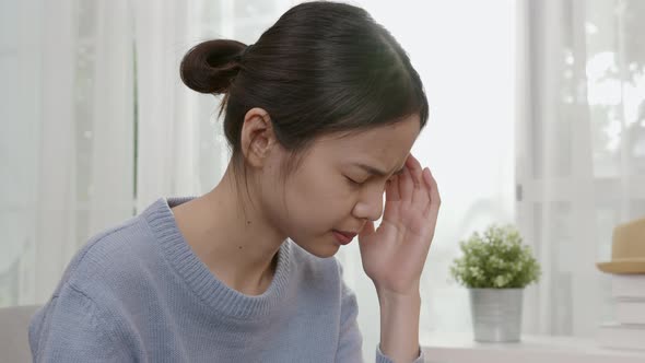 Tired young Asian woman sitting and have a headache because migraine