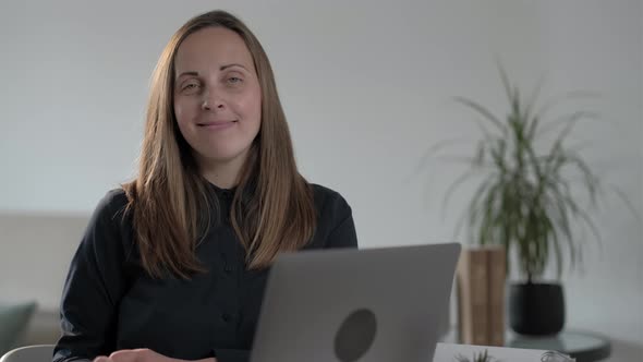 Smiling young woman freelancer with laptop looking at camera, distance online worker concept.