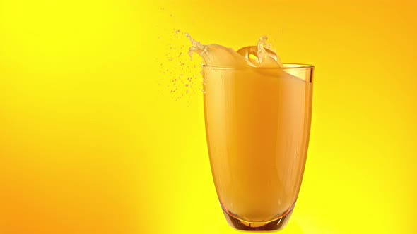 Super Slow Motion Shot of Ice Cubes Falling Into Glass of Orange Juice and Making Splash at 1000Fps