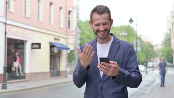 Man Celebrating Success on Phone While Walking Down the Street