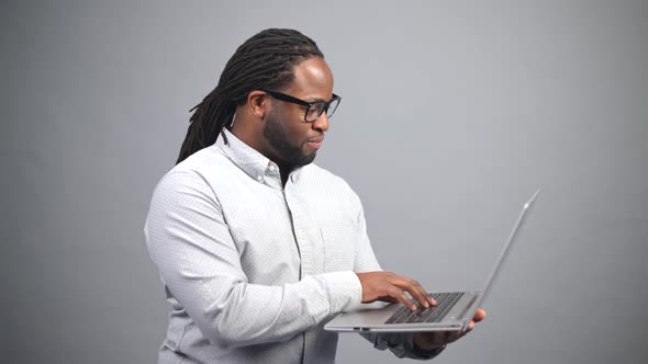 AfricanAmerican Guy Using the Laptop Isolated on Grey Background