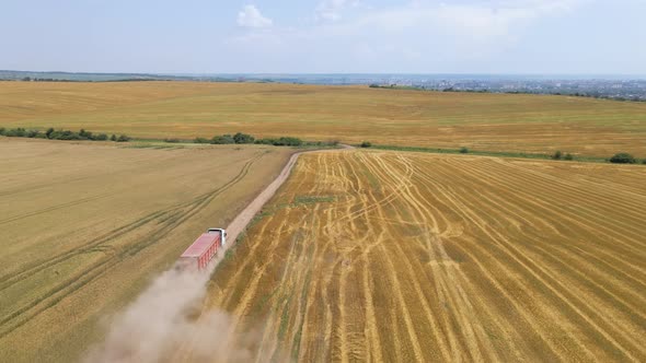 Aerial View of Lorry Cargo Truck Driving on Dirt Road Between Agricultural Wheat Fields