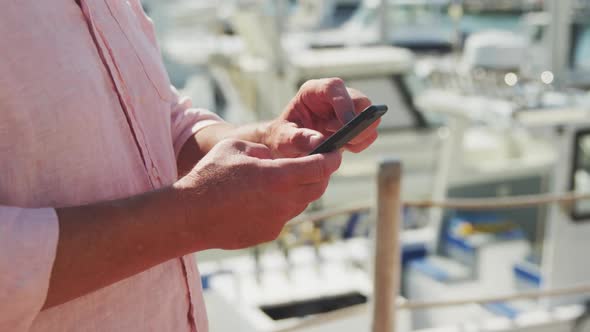 Side view mid section of a Caucasian man using his phone harbor side