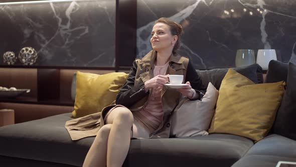 Portrait of Confident Caucasian Slim Woman Sitting on Comfortable Couch in Furniture Showroom