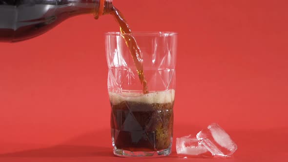 Pouring cola in glass cup in slow motion.