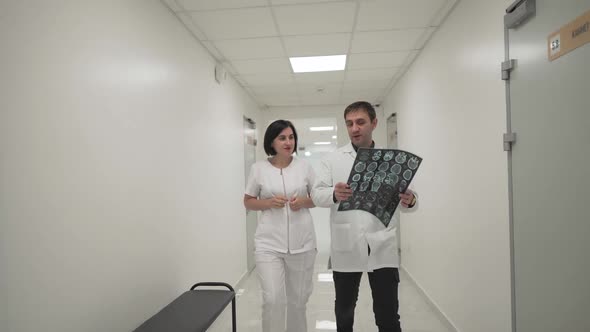 Two Doctors Walk Down Corridor and Discussing About Mri Brain Scan