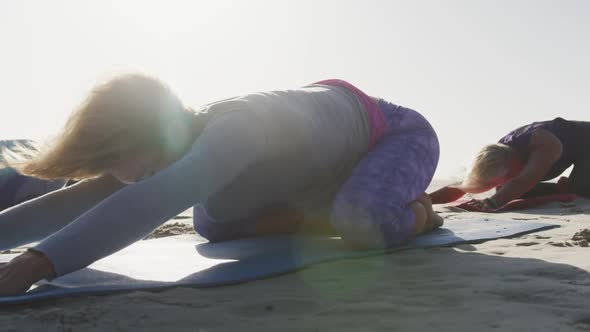 Athletic women performing yoga in the beach