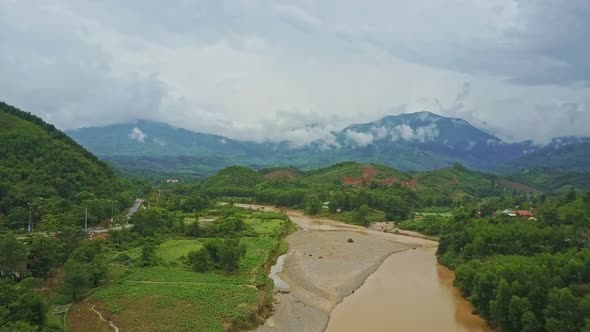 Aerial View River Runs Between Green Banks Against Mountains