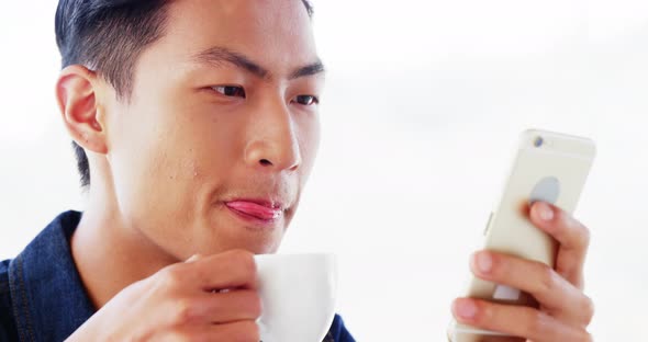 Man drinking coffee and using smartphone