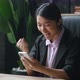 Asian Woman Sit at Desk Office Hold Smartphone Receive Message From Bank Feels Incredible Happy - VideoHive Item for Sale