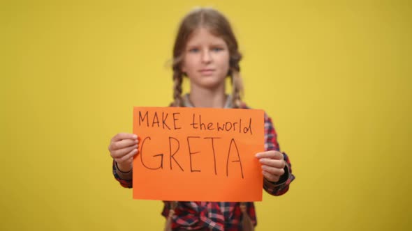 Blurred Serious Confident Teenage Girl Showing Make the World Greta Sign at Yellow Background