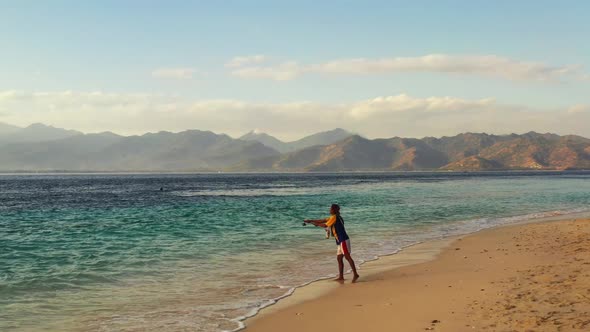 Male model fisherman on paradise island beach wildlife by blue green sea with white sandy background