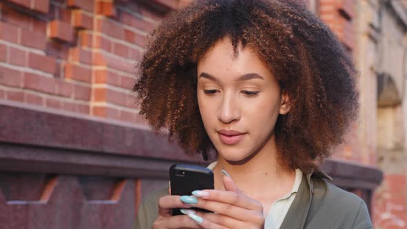 Young African American Woman Using Smartphone Surfing Social Media Checking News or Texting Messages