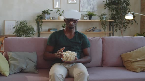 Black Man Eating Popcorn and Watching Movie on VR Headset