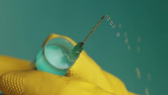 Syringe Needle with Liquid Dripping Drops of Medication in Doctor Hands