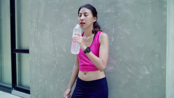 Young Asian drinking water because feel tiredt park. Lifestyle active women exercise in the city.