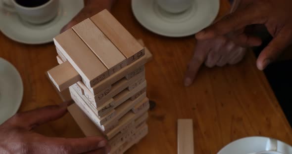 Friends playing jenga game on table while having coffee in bar 4k