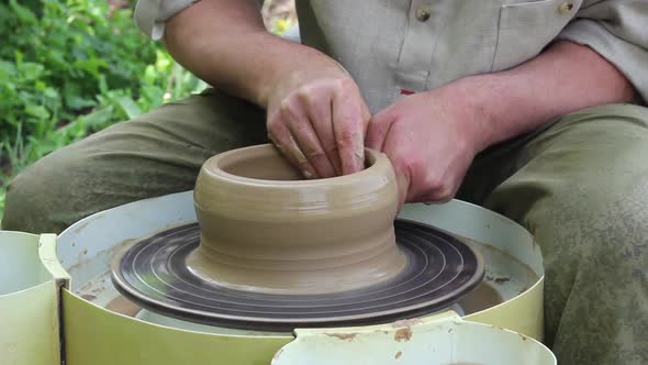 Male Potter of Caucasian Ethnicity in Working Uniform Makes a Clay Pot Closeup