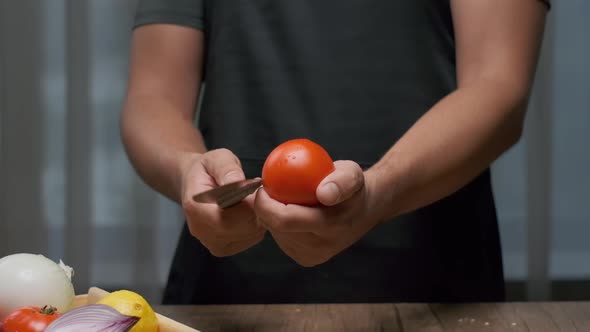 The Chef Cuts the Tomato While Holding It