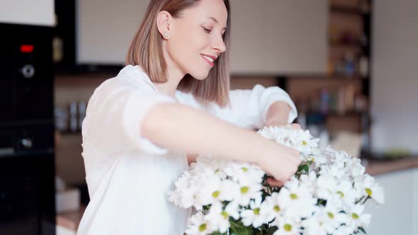 Beautiful Woman Putting Fresh White Flowers Into a Vase