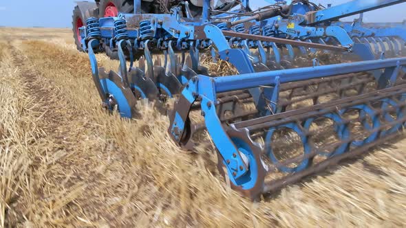 Rotary Cultivator and a Disc Plow on a Tractor While Working in the Field