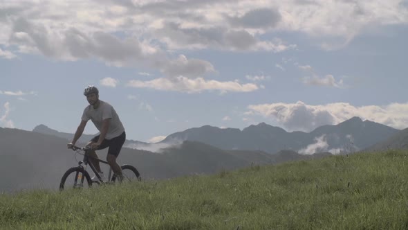 Young Athletic Man in Summer Day is Cycling Outdoor on Mountain with His Mountain Bike Slow Motion