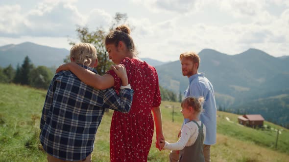 Hugging Family Enjoying Walk Green Slope Sunny Day