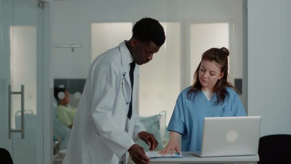Woman Working As Nurse Using Laptop to Help Doctor