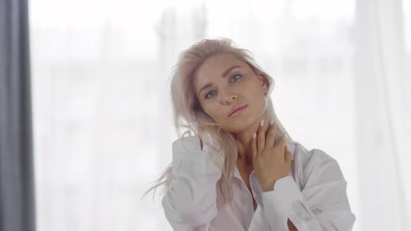 Young Caucasian Blonde Posing on Bed in White Shirt