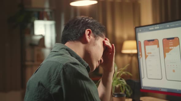 Tired Asian Male Mobile Application Developer Works With Graphics On His Personal Computer