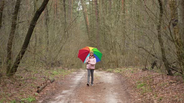 Girl with a Colorful Umbrella Walks in the Park