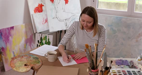 Young artist in studio taking notes in sketch book