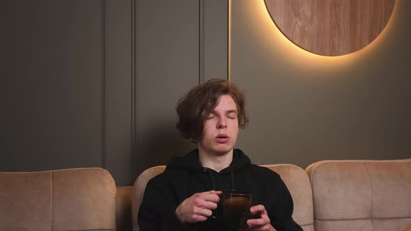 Portrait of Tired Man Sitting on Couch Drink Coffee or Tea