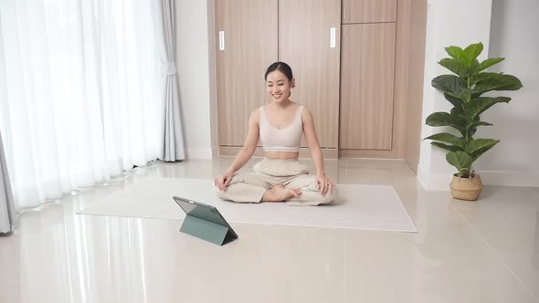 Woman studying online meditation on the floor in the living room to improve cons