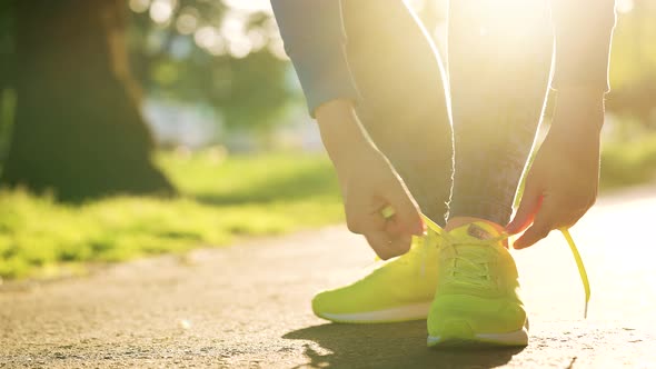 Woman Tying Shoelaces While Jogging or Walking at Sunset