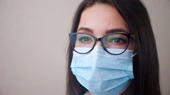 Close Up of Young Brunette Woman Doctor with Glasses and Light Blue Protective Mask