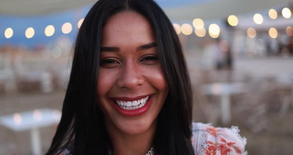 Young African girl smiling on camera with beach bar on background