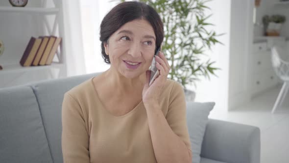 Portrait of Beautiful Senior Caucasian Woman Talking on the Phone. Pleasant Mature Brunette Lady