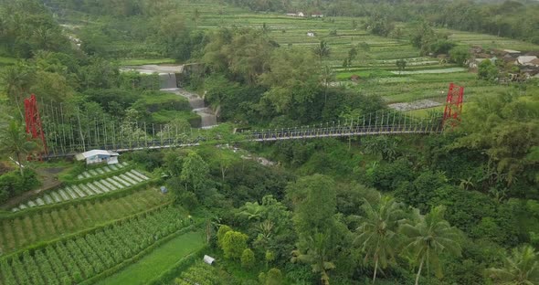 aerial drone view of suspension bridge, the valley and river with waterfall. mangunsuko bridge or Jo