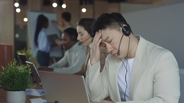 Asian Male Employee Suffering From Headache on Workplace