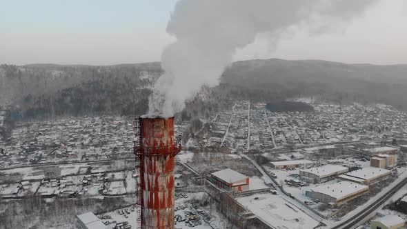 Industrial Zone with a Large Red and White Pipe Thick White Smoke is Poured From the Factory Pipe in