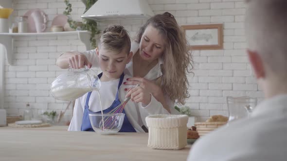 Pretty Woman and Her Teen Son Cooking in the Kitchen, the Boy Helping Mother To Make Food