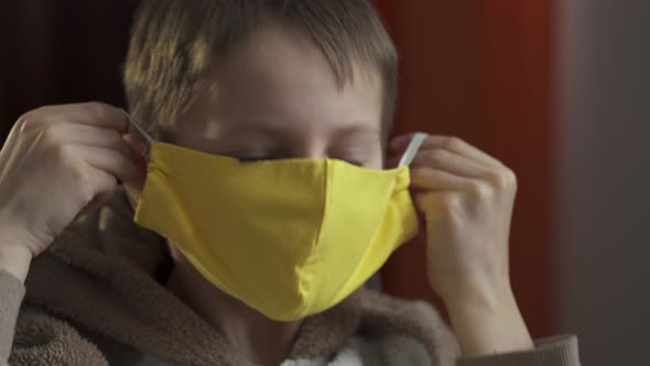 A Teenage Boy Wears a Yellow Protective Mask. Coronavirus Epidemic 2020.